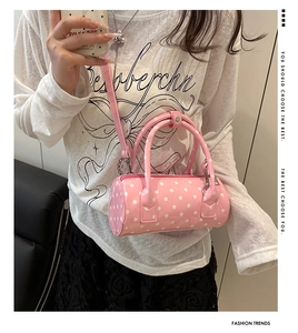 Pink polka dot barrel bag worn by model showing trendy style and compact size