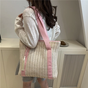 Beige woven straw tote bag with pink straps and white tassel charm for summer
