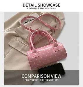 Close-up of pink polka dot patent leather cylinder bag with glossy finish and strap