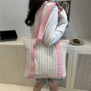 Handwoven cream straw tote bag with pink fabric straps and white tassels for summer