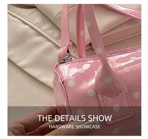Detailed shot of silver zipper and handle stitching on pink polka dot patent leather bag