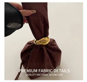 Détail du sac seau en daim marron foncé avec décor de bague en métal doré liquide