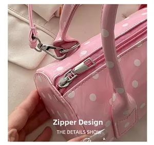 Close-up of a pink polka dot barrel bag featuring a metallic silver zipper and strap