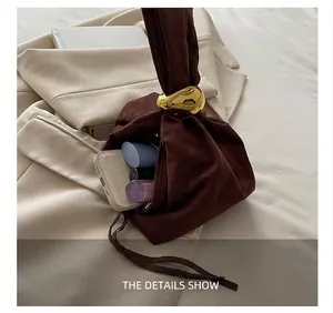 Capacité du sac seau en daim marron avec fermoir doré contenant téléphone et maquillage