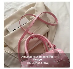 Detail of pink polka dot barrel bag showing adjustable shoulder strap and stitching