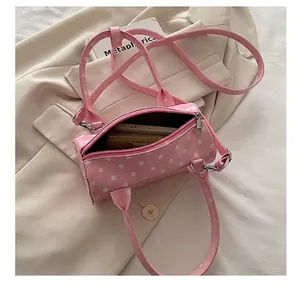 Internal capacity view of pink polka dot cylinder bag showing phone and wallet
