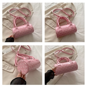 Detailed views of pink polka dot barrel bag with leather texture and shoulder strap