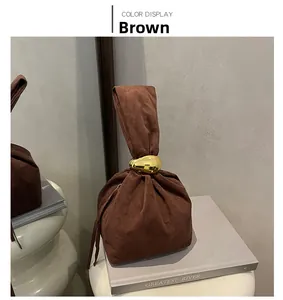 Détail du sac seau en daim marron avec quincaillerie dorée incurvée sur l'anse