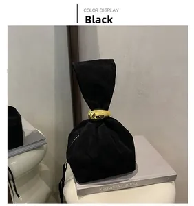 Détail d'un sac seau en daim noir avec boucle dorée galet et frange à pampilles longues
