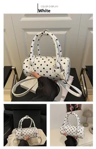Detailed close-up of white cylindrical crossbody bag with black polka dots and smooth finish