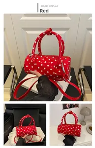 Detailed views of red polka dot barrel bag in hand and gift box arrangement