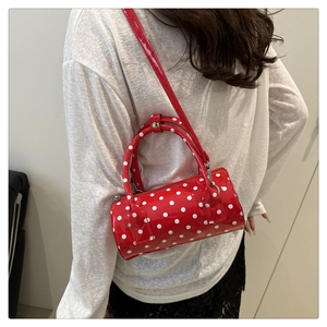 Detailed view of a red polka dot cylinder bag with glossy finish and top handles