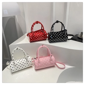 Polka dot cylindrical bags in red, black, white, and pink on minimalist display