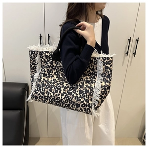 Detail of leopard print tote bag featuring white fringe tassels and thick rope handles
