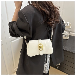 Detail of a white patent leather shoulder bag with a gold metal buckle on a black blazer
