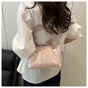 Detailed embroidery of 3D butterflies on a pink lace bucket bag shown with a model