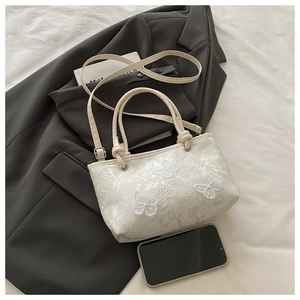 Détail de sac cabas en dentelle blanche avec papillons 3D et bandoulière fine