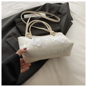 Détail du sac à main en dentelle blanche avec broderie papillon délicate sur le tissu