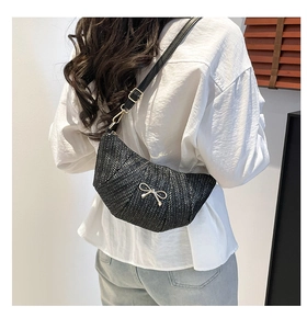 Detail showing woven texture and silver bow accent on a black crescent crossbody bag