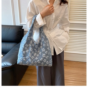 Detailed view of light blue tote bag with 3D floral textures and wide shoulder straps