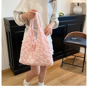 Detailed macro view of pink knit tote bag with 3D white flower embroidery texture