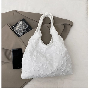 Detail of white tote bag with 3D floral texture fabric and minimalist curved design