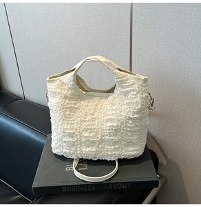 Détail du sac à main blanc plissé avec ferrures dorées et bandoulière amovible