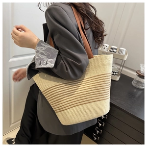 Detail shot of woven straw tote bag with brown stripes worn by model for a summer look