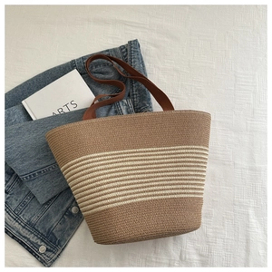 Detail of French woven straw tote bag with beige stripes and comfortable brown straps