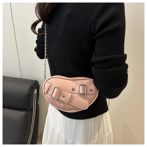 Détail d'un sac rose en forme de cœur avec des boucles argentées et une bandoulière chaîne