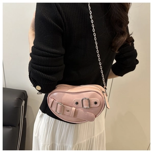 Détail du sac à main rose en forme de cœur avec bandoulière chaîne porté par un mannequin