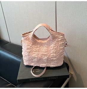 Détail de la texture froncée rose et des bandoulières amovibles du sac à main