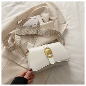 Detail of a creamy white leather saddle bag featuring a wide geometric fabric strap