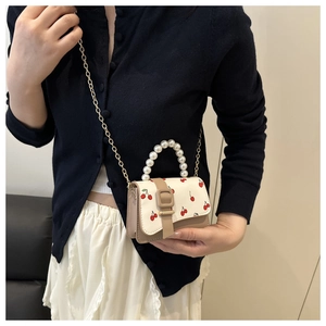 Detail of mini crossbody bag with cherry prints, pearl handle and gold chain strap