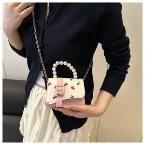 Detail of mini crossbody bag with cherry print, pearl handle and gold chain strap