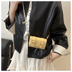 Detail of yellow crossbody bag featuring decorative buckles and transparent chain strap