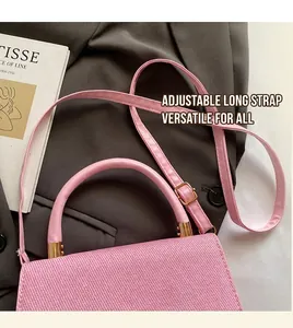 Detail of pink crossbody bag with textured fabric, gold hardware and long strap