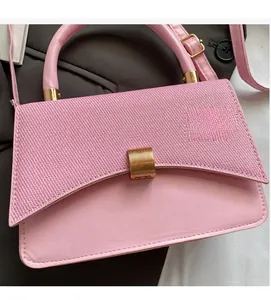 Detailed shot of pink textured woven flap and smooth leather small square bag with gold clasp