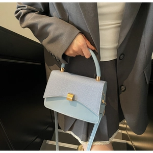Détail du sac à main bleu clair en cuir avec texture tressée et boucle dorée