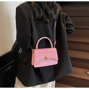 Detailed view of pink leather crossbody bag with gold lock buckle and fine texture