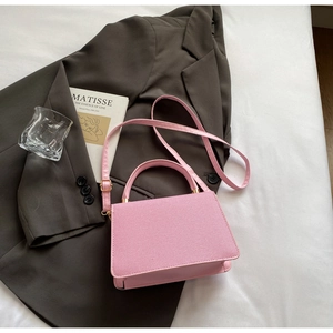 Close-up of pink structured handbag with gold hardware and fine textured finish