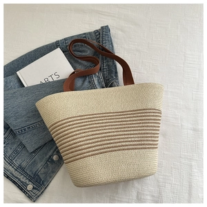 Detail of woven straw tote bag featuring beige and brown stripes for summer