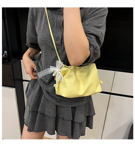 Detail of lemon yellow crossbody bag with delicate white lace and pearl bow decoration