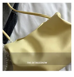Close-up of yellow soft leather cloud bag featuring large pearl embellishments and strap