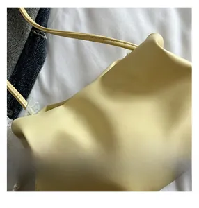Close-up of yellow soft leather cloud bag featuring large pearl embellishments and strap