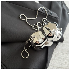 Macro view of metallic silver liquid-shaped bag with floral lid and snake chain