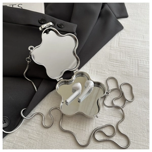 Detailed macro view of silver flower-shaped metal clutch with inner double mirrors