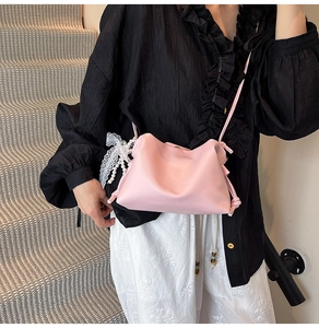 Pink pleated cloud bag with lace bow and pearl charm shown on a female model
