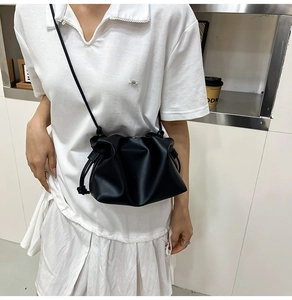 Model wearing a black ruched cloud bucket bag made of soft PU leather with crossbody strap