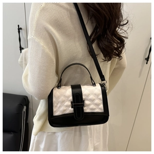 Detail of a quilted black and white crossbody bag featuring a metallic buckle and strap
